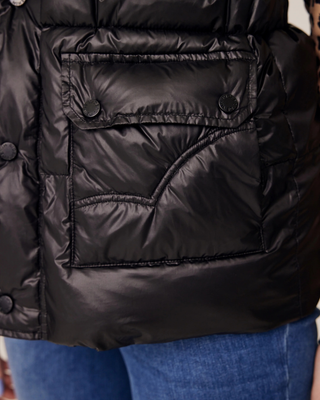 Close-up van de veilige voorzakken op de zwarte pufferbodywarmer, met nadruk op het praktische ontwerp voor ruiters.
