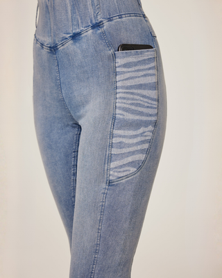 Schuin vooraanzicht van de lichtblauwe jeansrijbroek waarbij de decoratieve mobiele zak met zebraprint wordt uitgelicht.