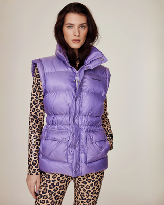 Model draagt het lila riding puffer vest dichtgeritst, gestyled met een bijpassende rijbroek met luipaardprint.