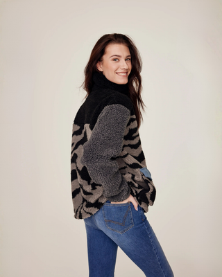 Schuin achteraanzicht van het lila en zebra teddyjack met de hand van het model in de achterzak van haar denim rijbroek. 