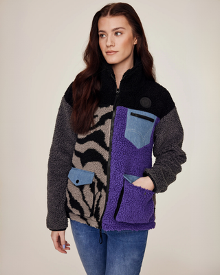 Model kijkt opzij met een hand in de zak en toont het functionele ontwerp van het lila en zebra teddyjack.