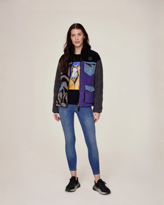 Volledige lichaamsfoto van een model dat een open lila en zebrajack draagt over een zwart T-shirt en OG denim rijbroek.
