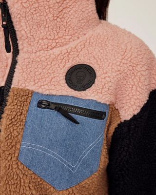 Gedetailleerde opname van de borstzak met een rits en het kenmerkende Riders Denim-logo op het roze paneel.