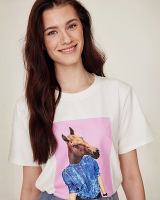 Close-up portret van een glimlachend model dat het witte T-shirt met horsie-print draagt, wat een warme en vriendelijke paardensportstijl laat zien.