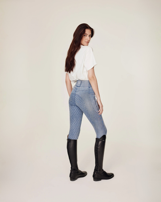 Volledig achteraanzicht van het witte horsie T-shirt, gestyled met lichtblauwe rijtights.