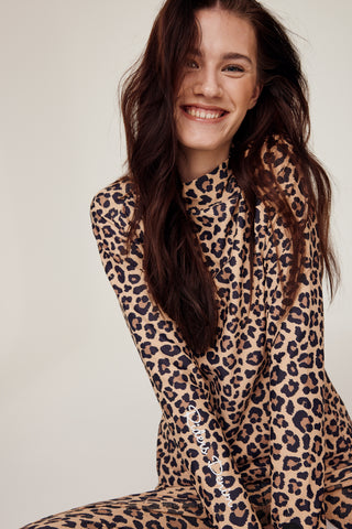 Lachend model dat zit en de complete rijset met luipaardprint van Riders Denim draagt.
