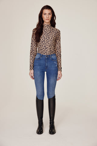 Volledig vooraanzicht van een model dat de Leo rijtop toont, gecombineerd met een originele denim rijbroek.